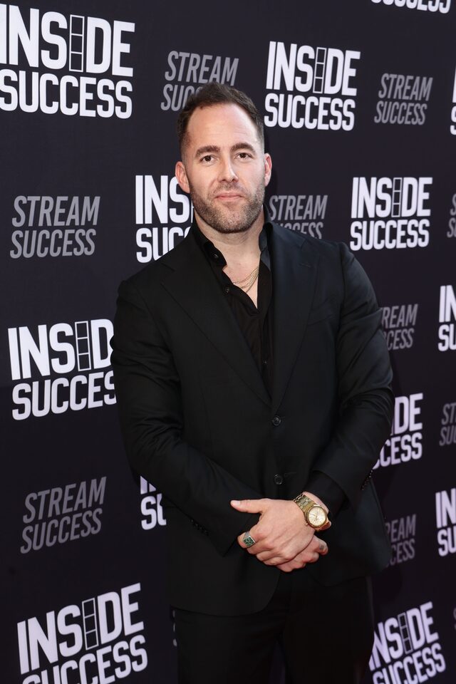 Justin Day in a black suit at a media event